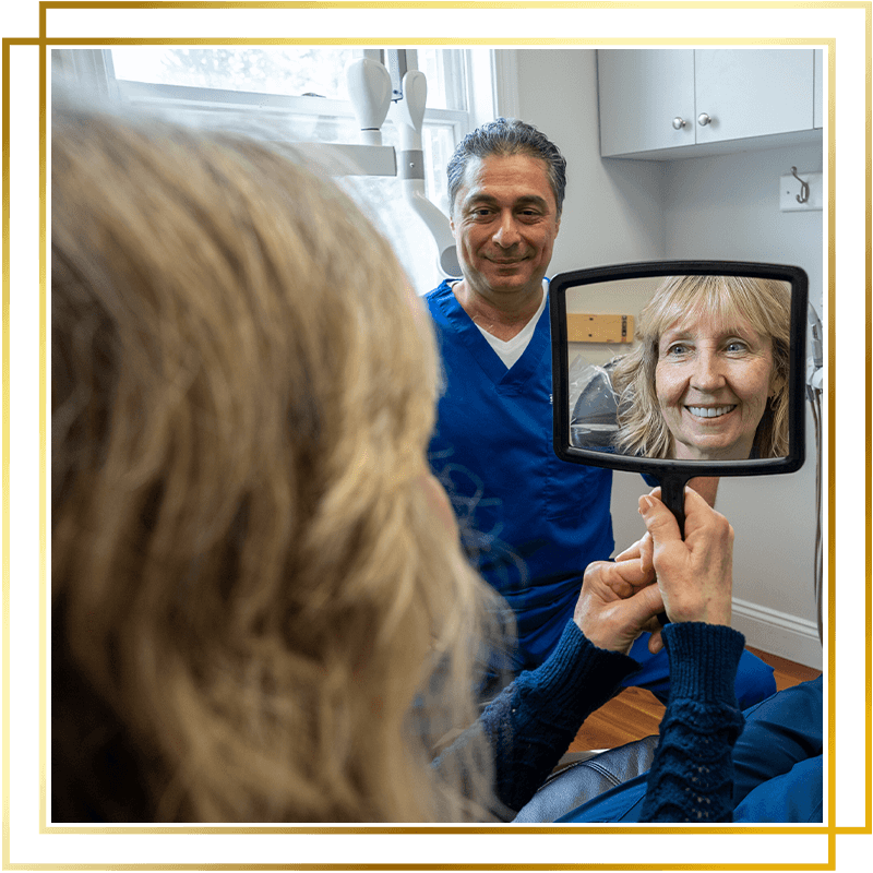 Team member looking at her new teeth after dental procedure